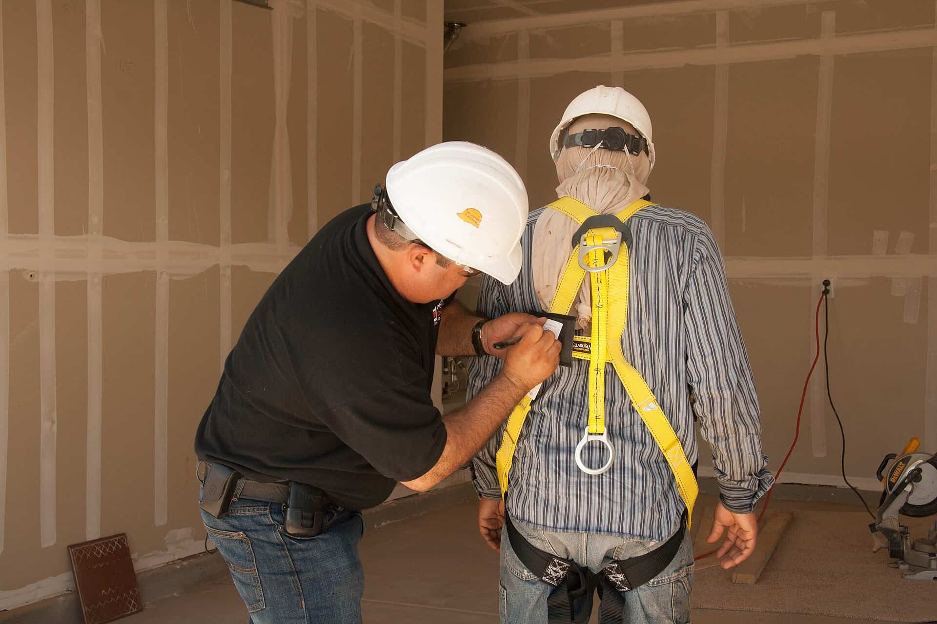 A construction worker wearing fall-protection equipment on scaffolding