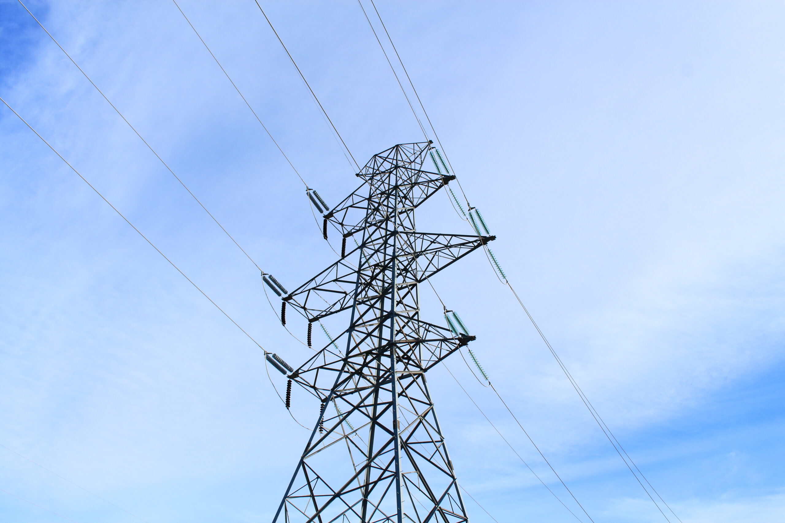 A high-voltage electricity transmission tower against an open sky