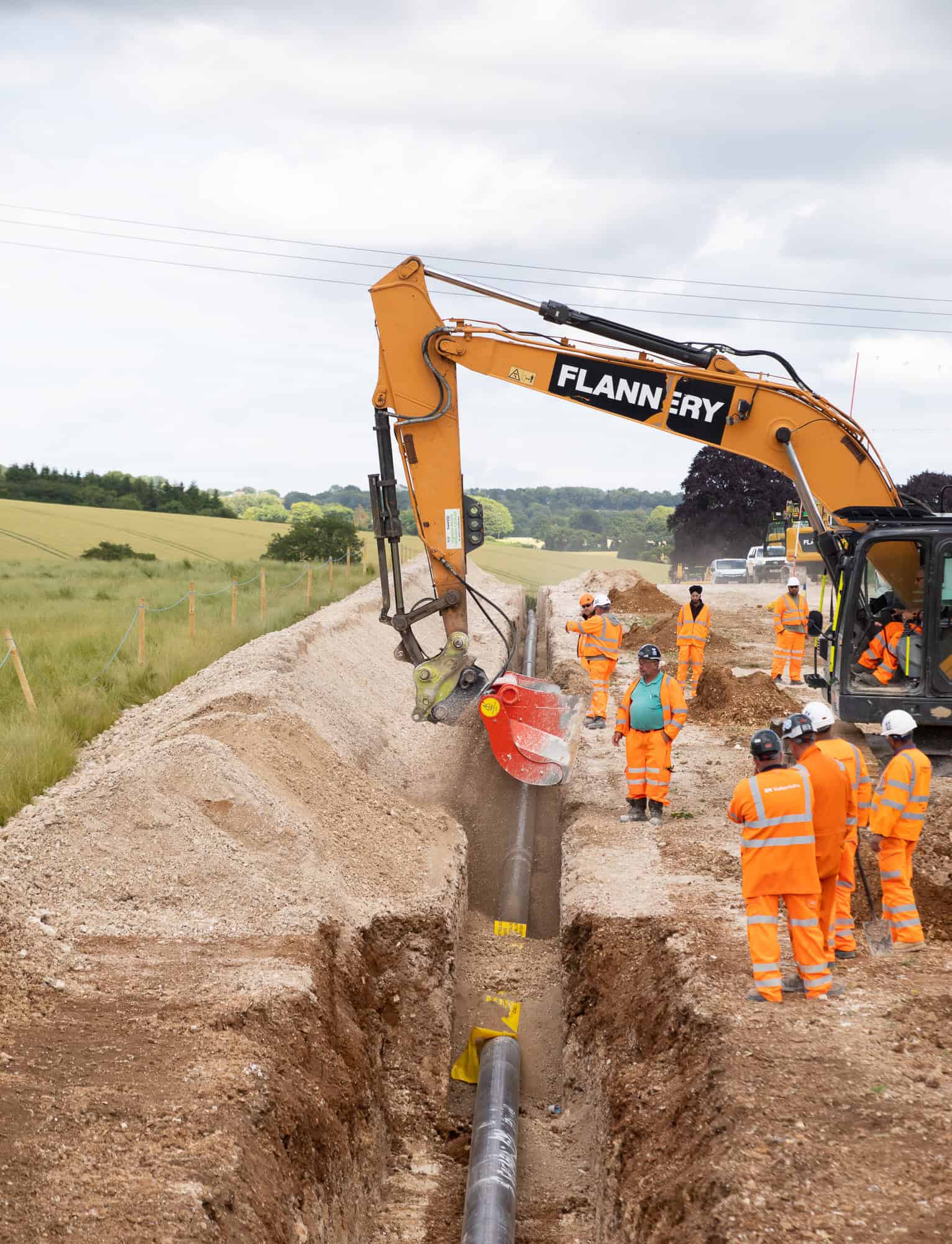 An excavator working alongside an open construction trench