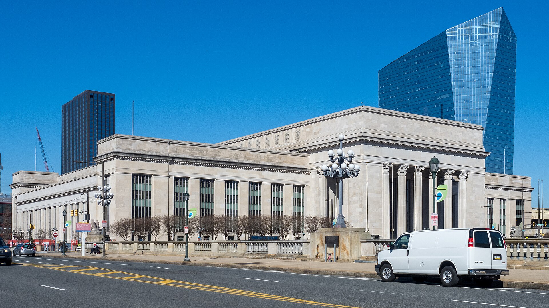 The neoclassical limestone exterior of William H. Gray III 30th Street Station in Philadelphia with the Cira Centre tower behind it