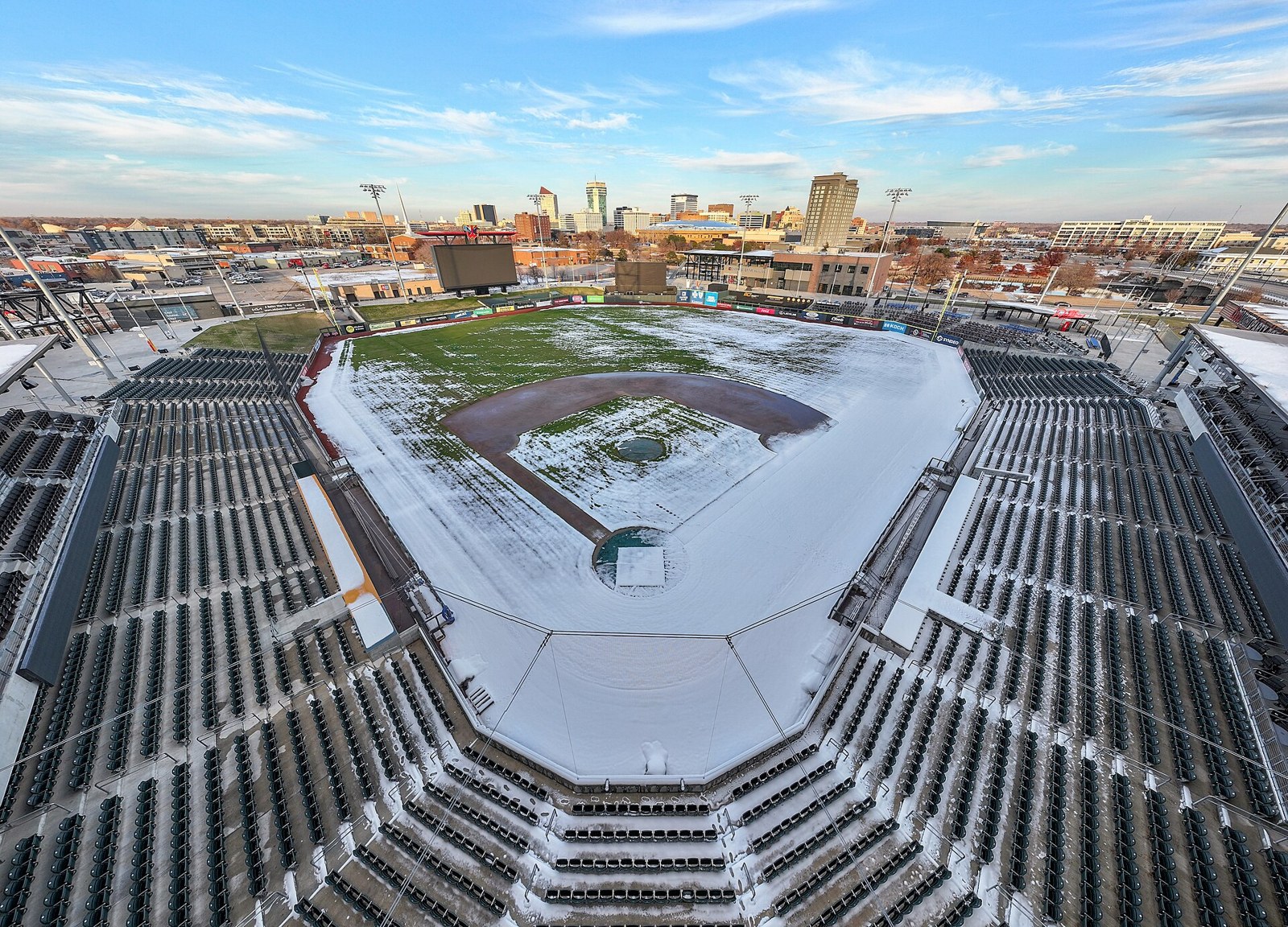 Equity Bank Park in Wichita, with the downtown skyline behind it; the Delano Ballpark District hotel site sits across the street