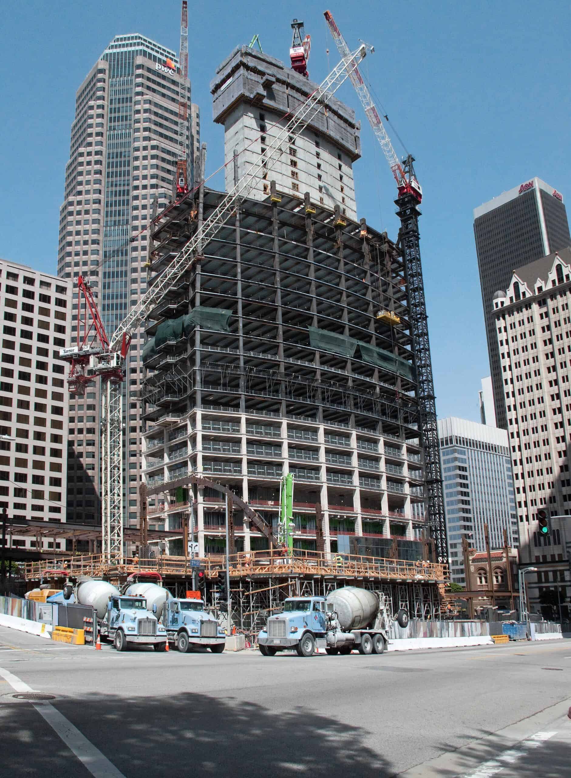 High-rise office tower under construction with tower cranes above the top floors