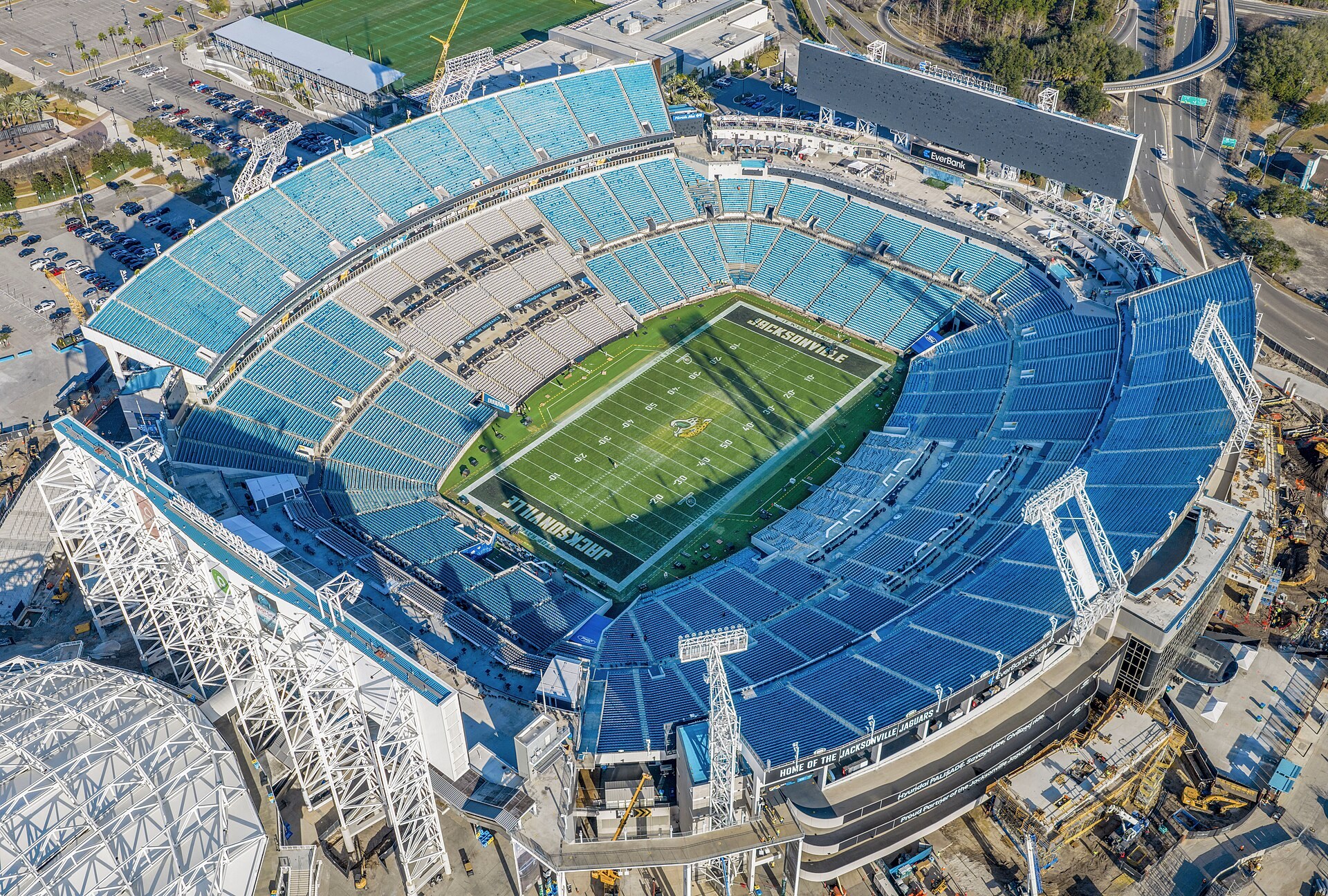 Aerial view of EverBank Stadium in Jacksonville in January 2026 with new steel canopy trusses rising along the sidelines and construction staging at the corners