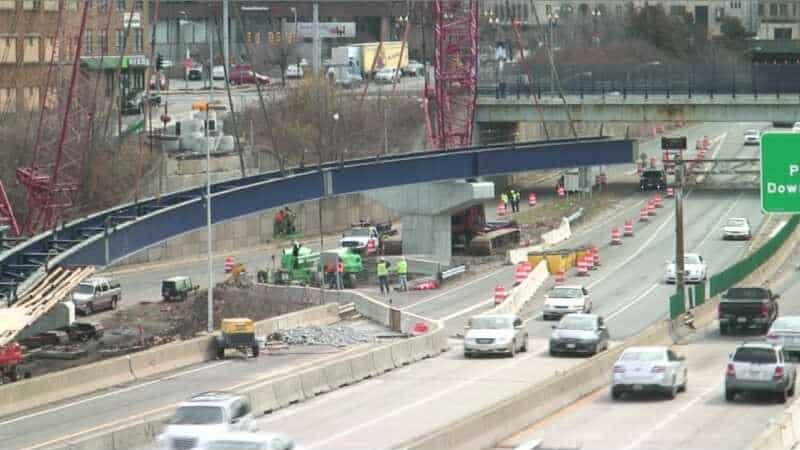 Crews setting a steel girder span across an interstate highway