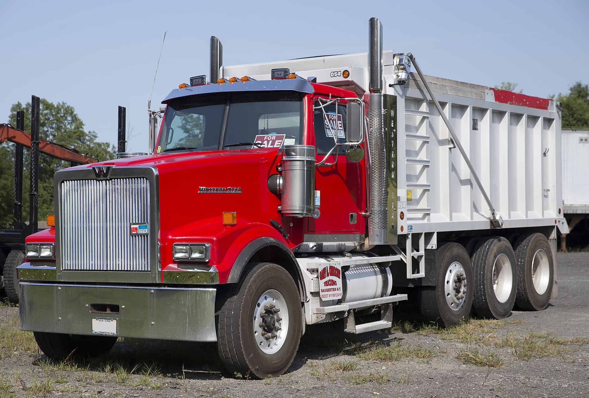 Red Class 8 dump truck with an aluminum dump body, viewed from the front left