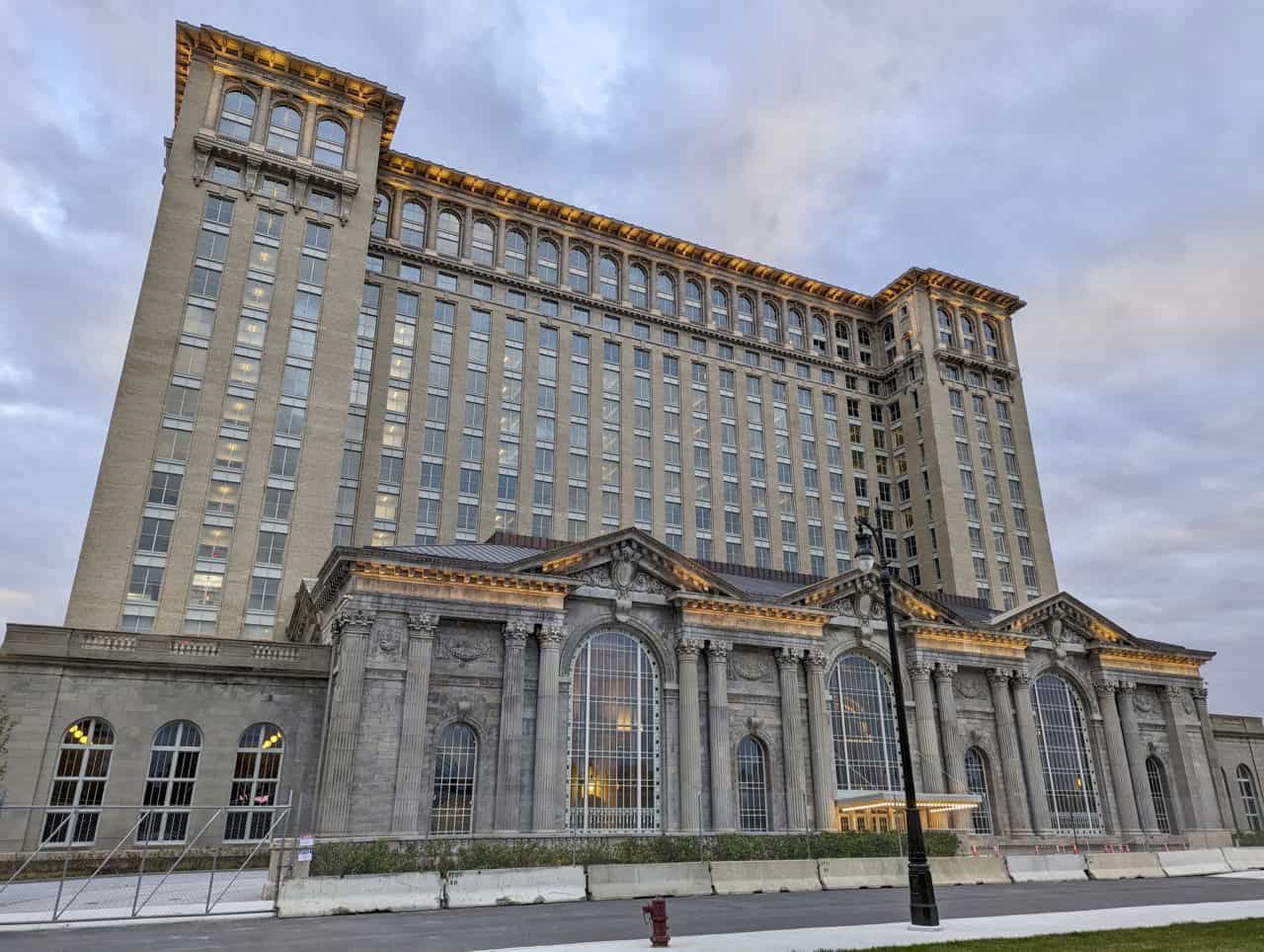 Restored Michigan Central Station in Detroit at dusk, with the office tower and the arched terminal head house lit from within