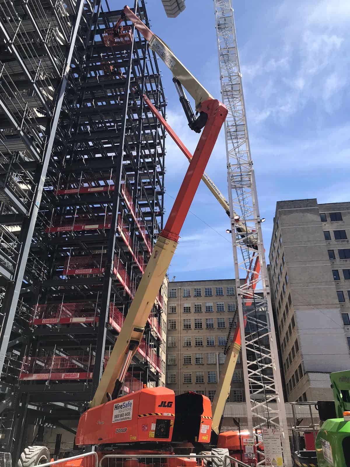 Telescopic boom lift working alongside scaffolding on a city jobsite