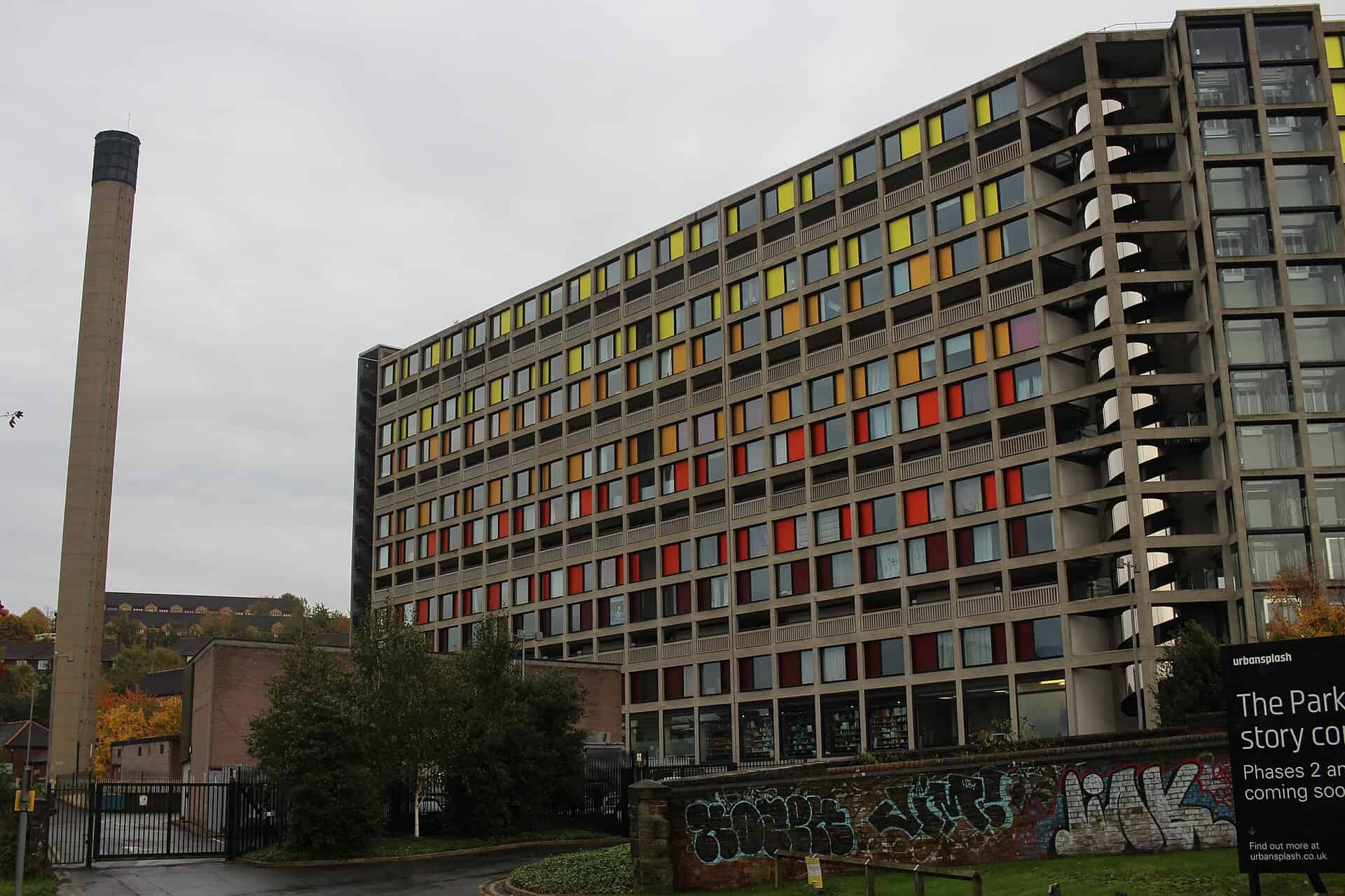 Restored Park Hill housing block in Sheffield with exposed concrete frame infilled with red, orange and yellow anodised panels
