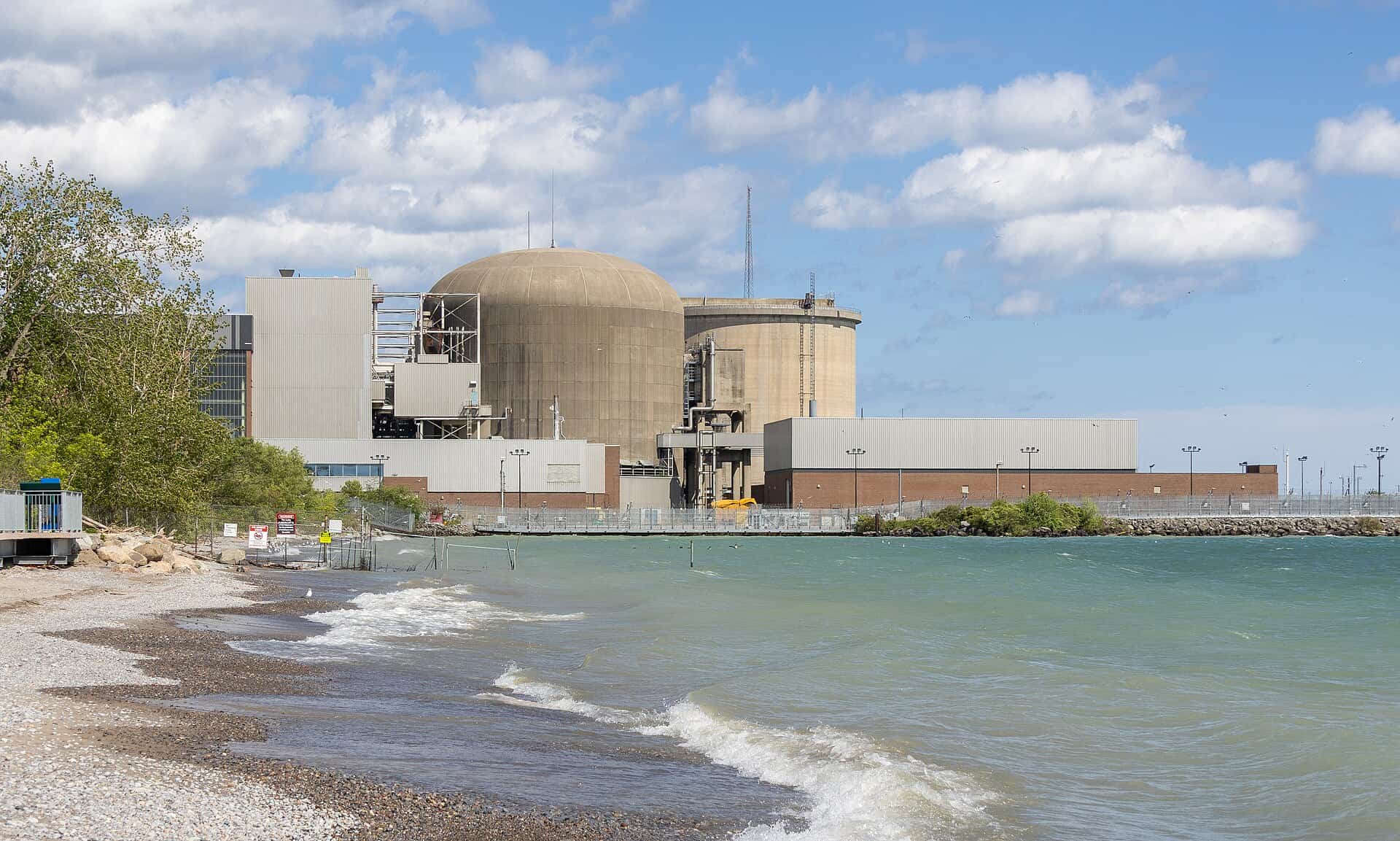 Pickering Nuclear Generating Station on the Lake Ontario shoreline, with the vacuum building dome and reactor halls behind a seawall
