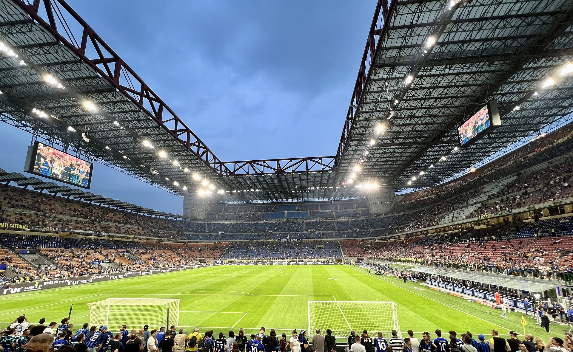 Exterior of the Stadio Giuseppe Meazza in Milan, showing the spiral access ramps and cantilevered red roof girders added for Italia '90