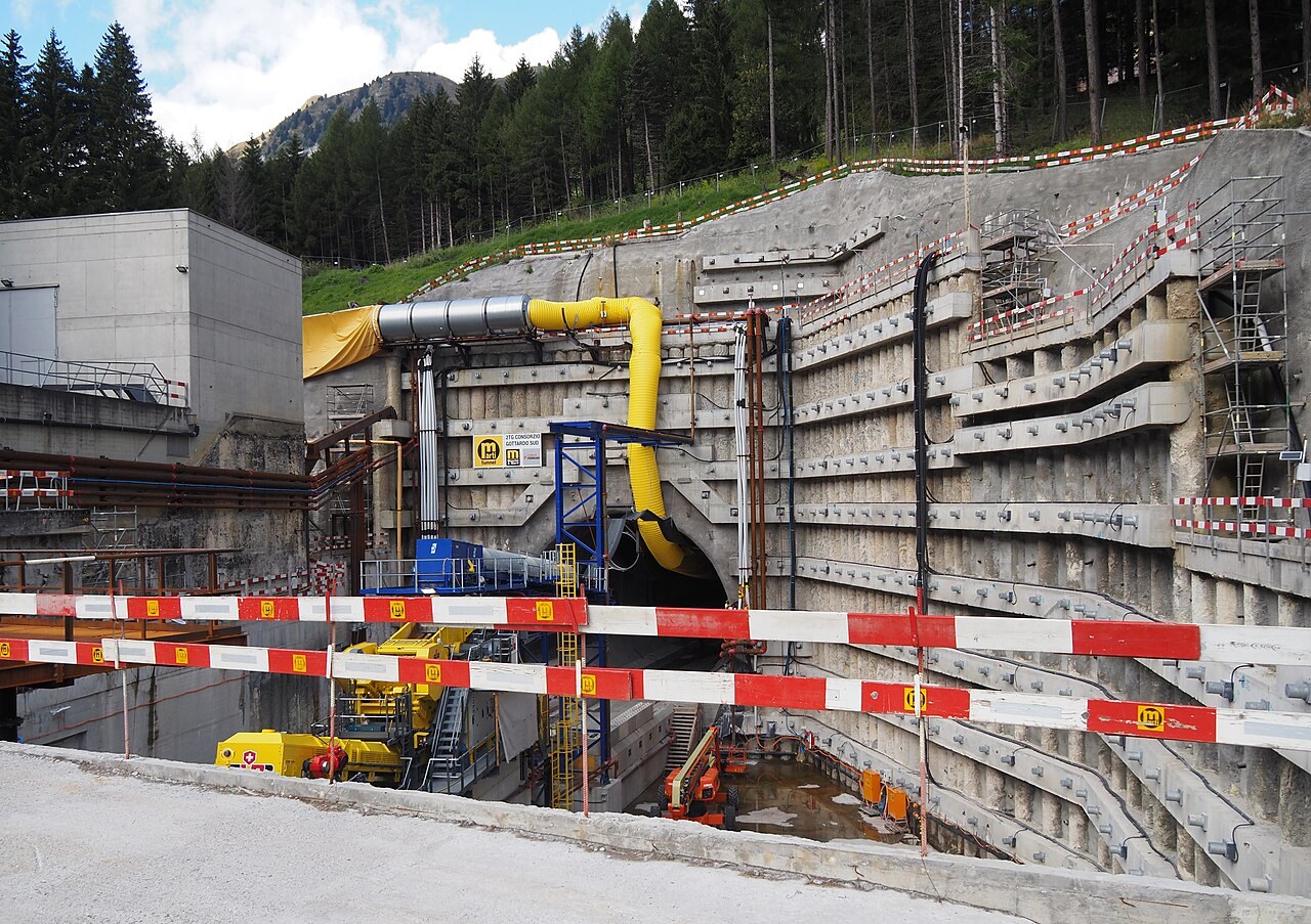 Approach trench and portal of the second Gotthard road tube at Airolo, with a yellow ventilation duct and a 2TG Consorzio Gottardo Sud sign, September 2025