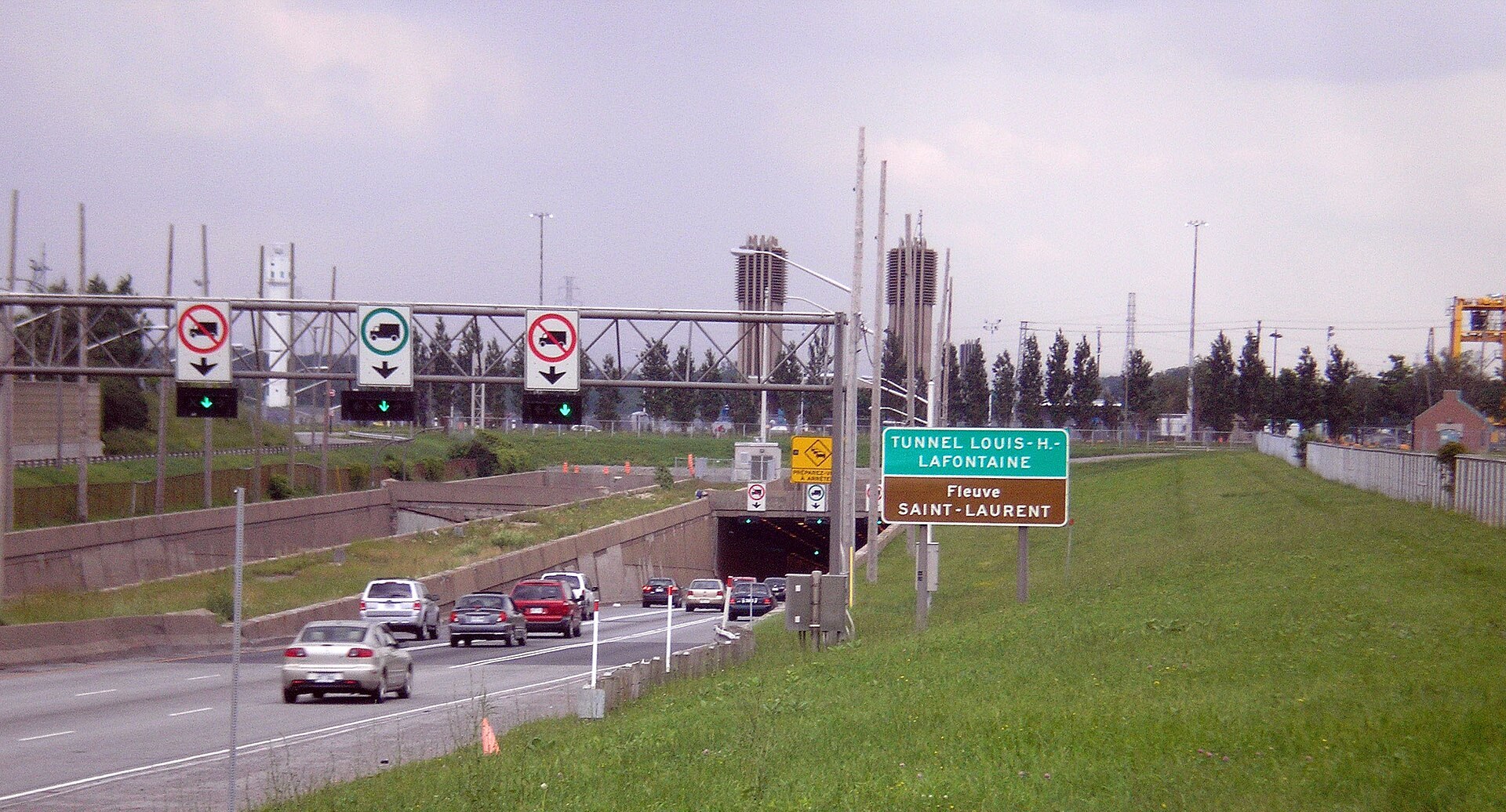 North (Montreal) portal approach with traffic entering, overhead lane-control gantry and a ventilation tower