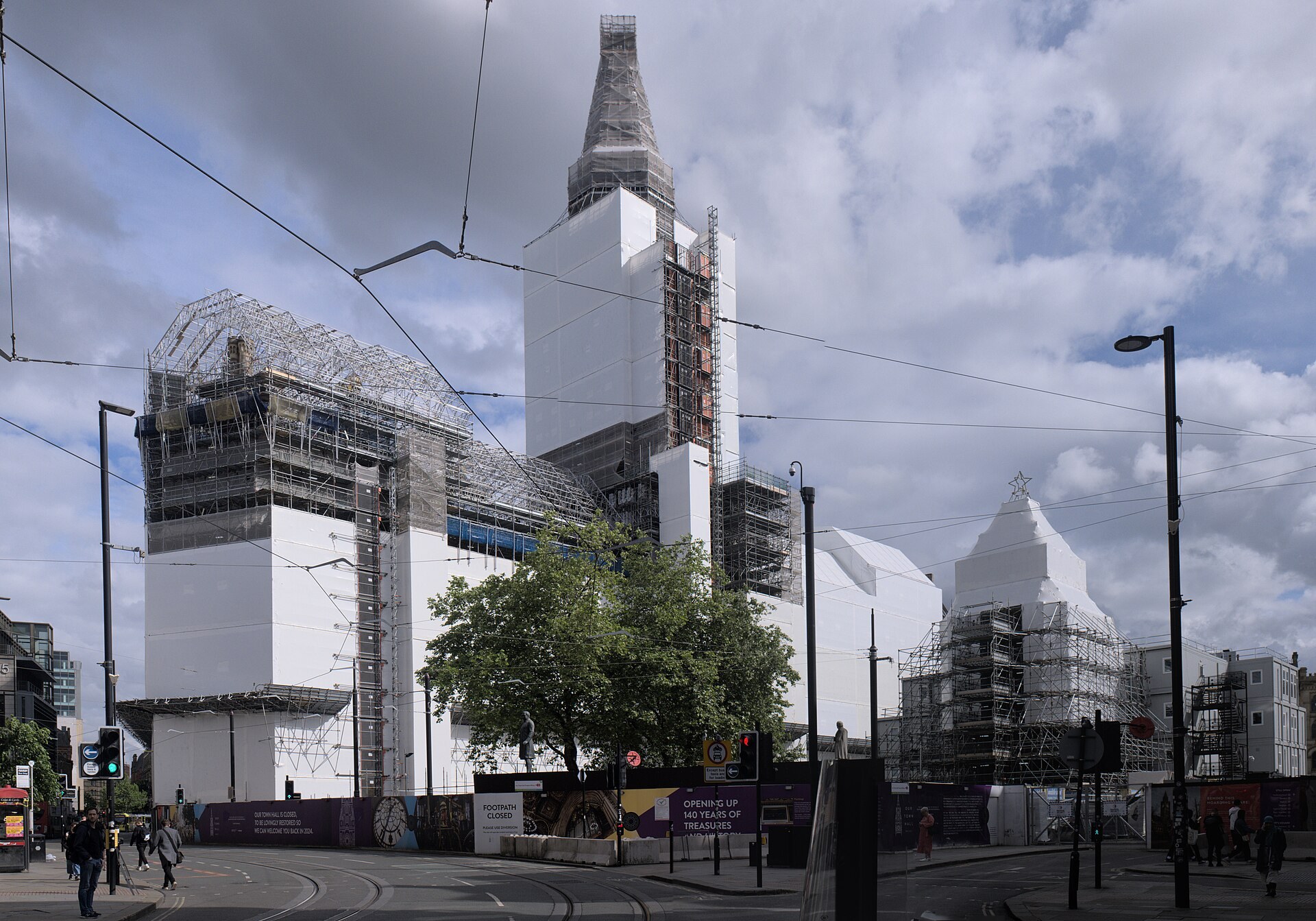 The Town Hall fully wrapped in scaffold and white sheeting, clock tower included, seen across the tram lines from the Princess Street side